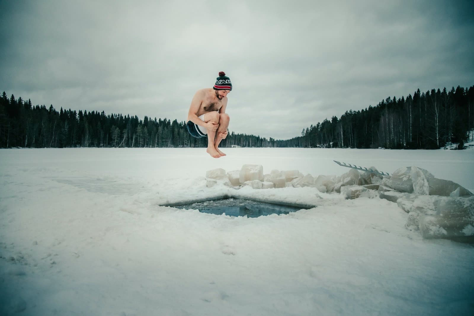 A man jumping into an ice swimming hole cut into a frozen lake